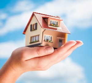 House in the hands of the man on a background of blue sky
